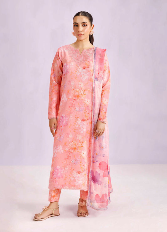 Woman wearing a blush pink floral printed lawn suit with embroidered neckline and matching pants, standing against a neutral background