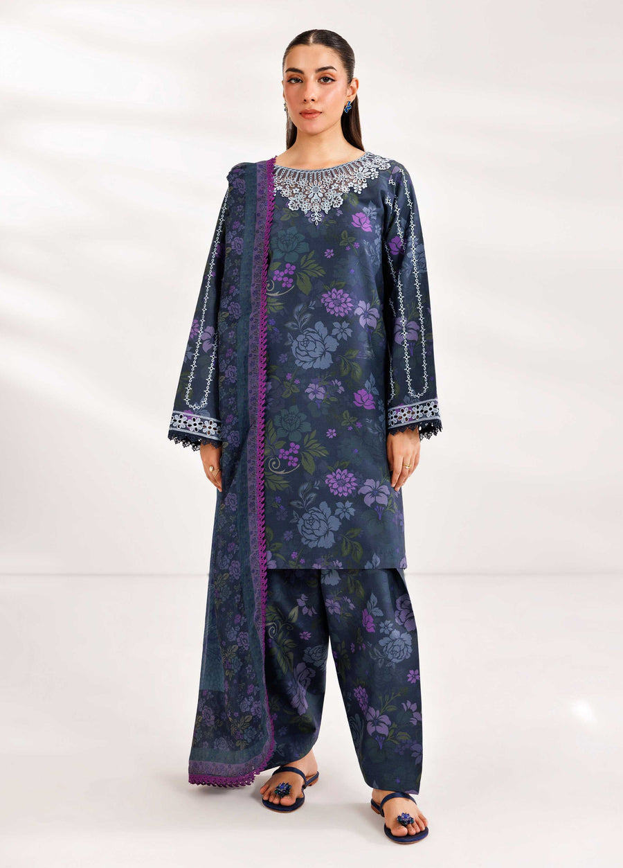 Woman wearing a navy blue floral three-piece embroidered suit with white lace embroidery on neckline and sleeves, paired with matching dupatta and loose trousers.