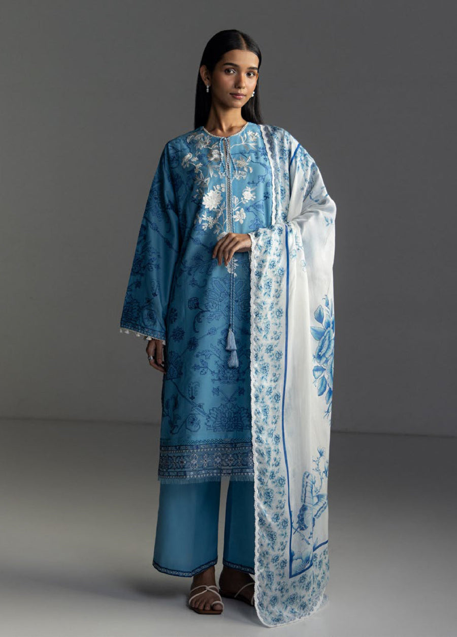 Woman wearing blue embroidered lawn shirt with tassel neckline, matching blue trousers, and white floral printed dupatta with lace border
