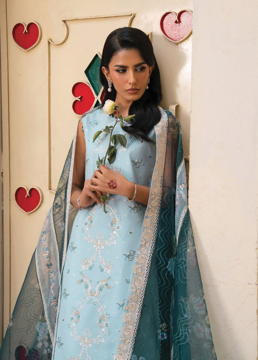Close-up of woman wearing embroidered lawn suit and holding a white rose, showcasing detailed floral embroidery and an organza dupatta with lace borders.