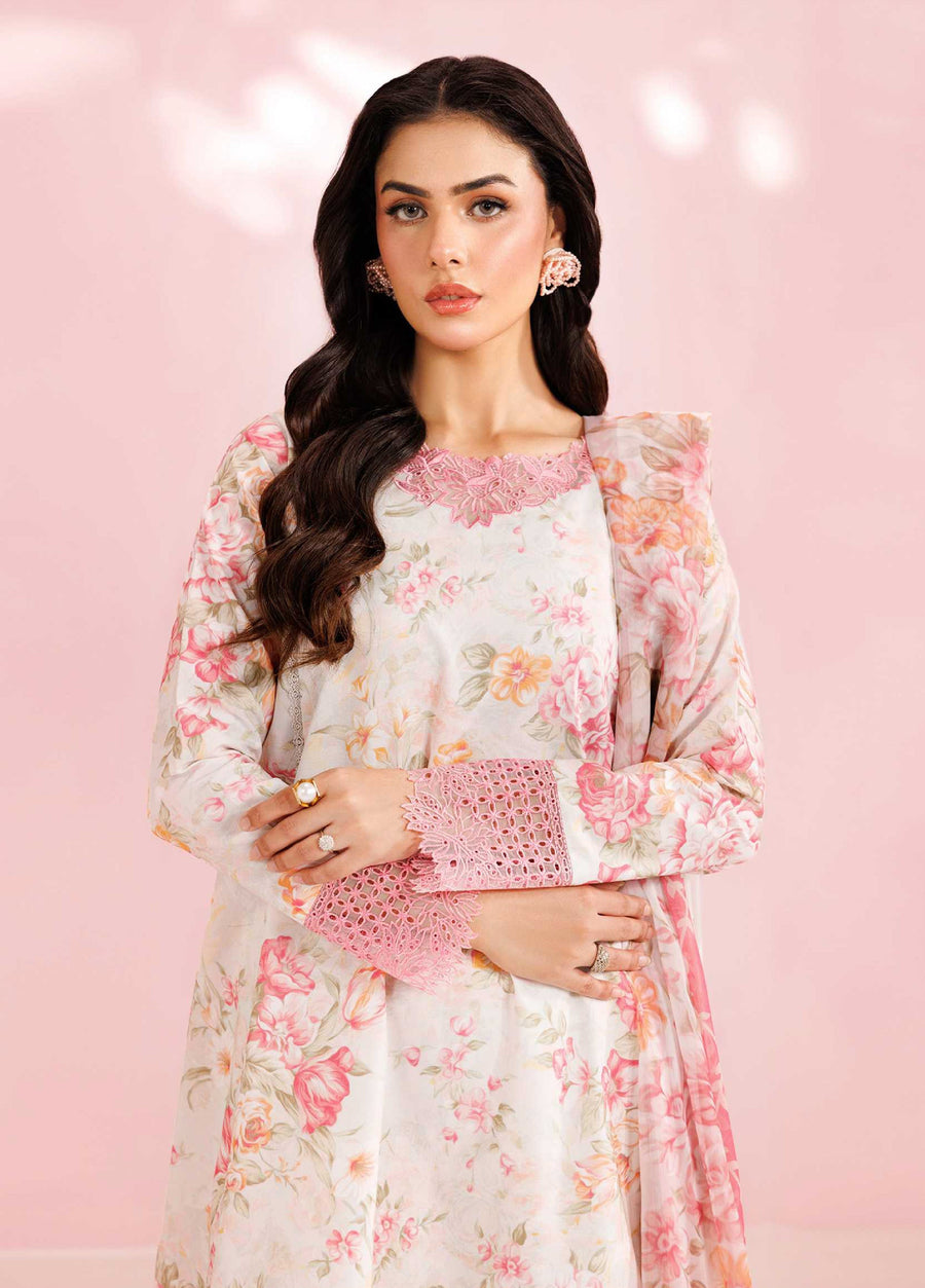 Close-up of woman wearing cream floral lawn suit showing detailed pink embroidery on neckline and sleeves, accessorized with elegant earrings and rings