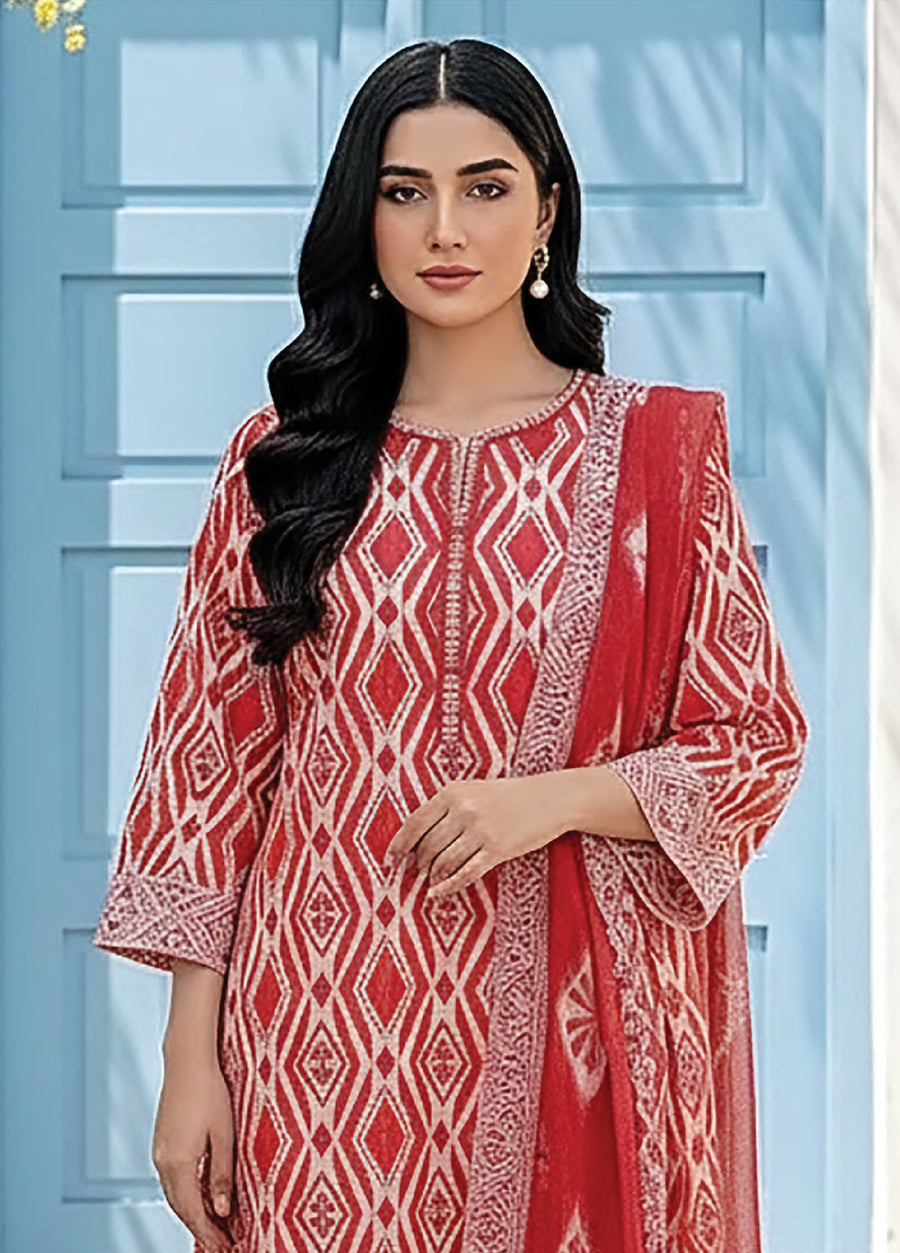 Close-up view of a woman dressed in a red and white geometric printed lawn shirt with 3/4 sleeves, accessorized with pearl drop earrings.