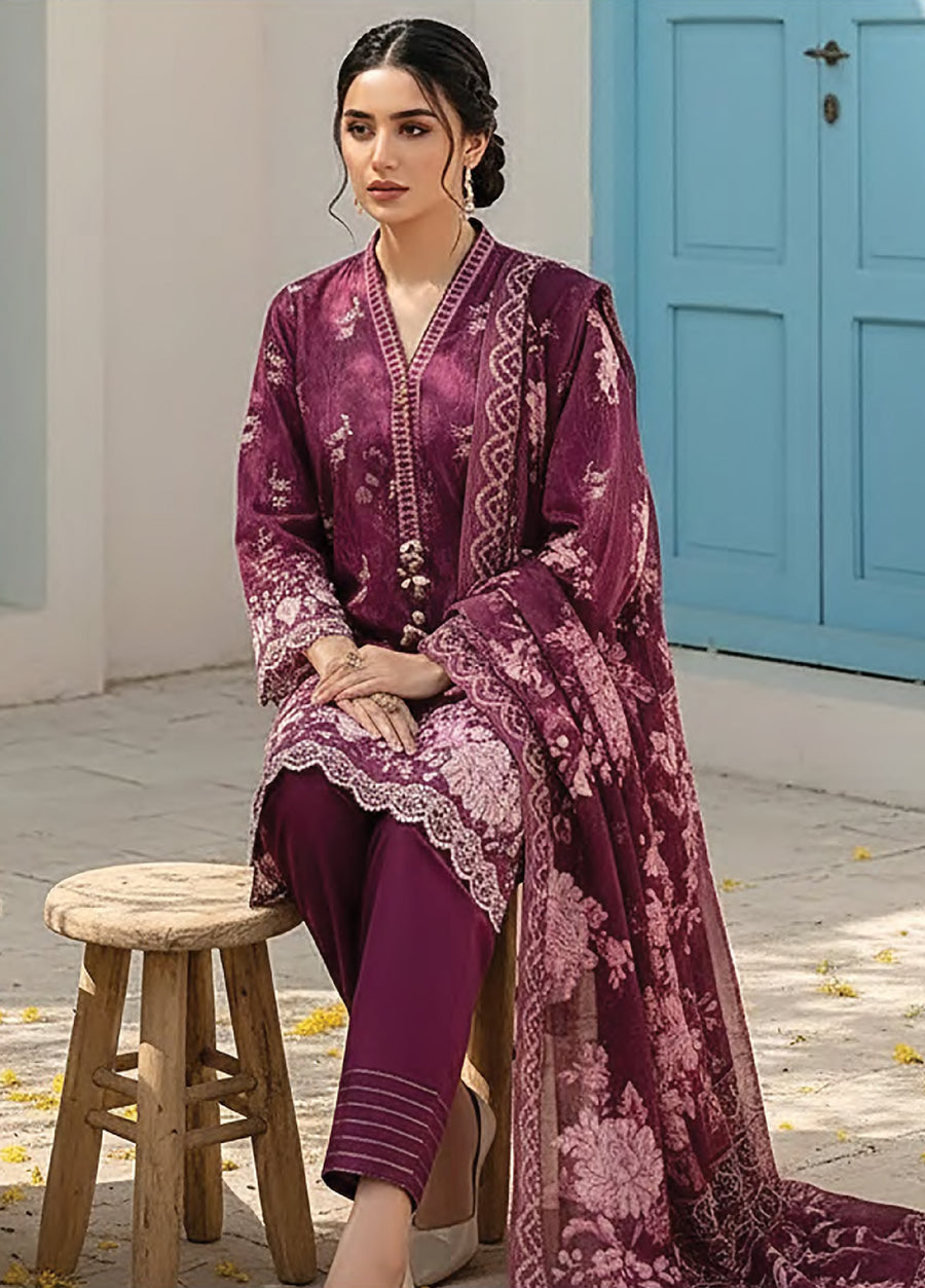Woman seated outdoors wearing deep plum floral printed lawn suit with plain dyed trousers and elegantly draped matching dupatta