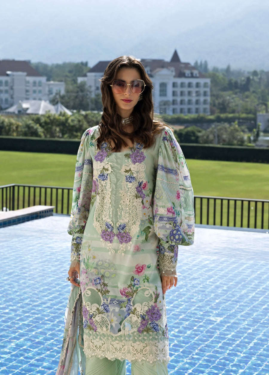 Close-up front view of woman in pastel green floral embroidered lawn suit with lace neckline and full embroidered sleeves standing near the pool