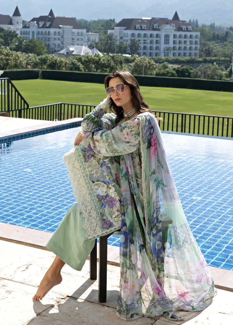 Woman seated by pool in pastel green embroidered lawn suit holding sheer floral chiffon dupatta draped over shoulder, showcasing intricate embroidery
