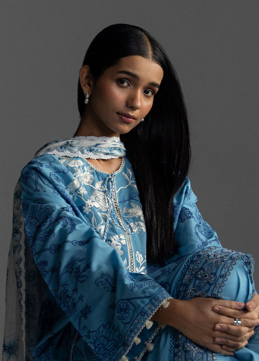 Front close-up of woman wearing blue embroidered shirt with tassels on sleeves and necklace, paired with white floral printed dupatta