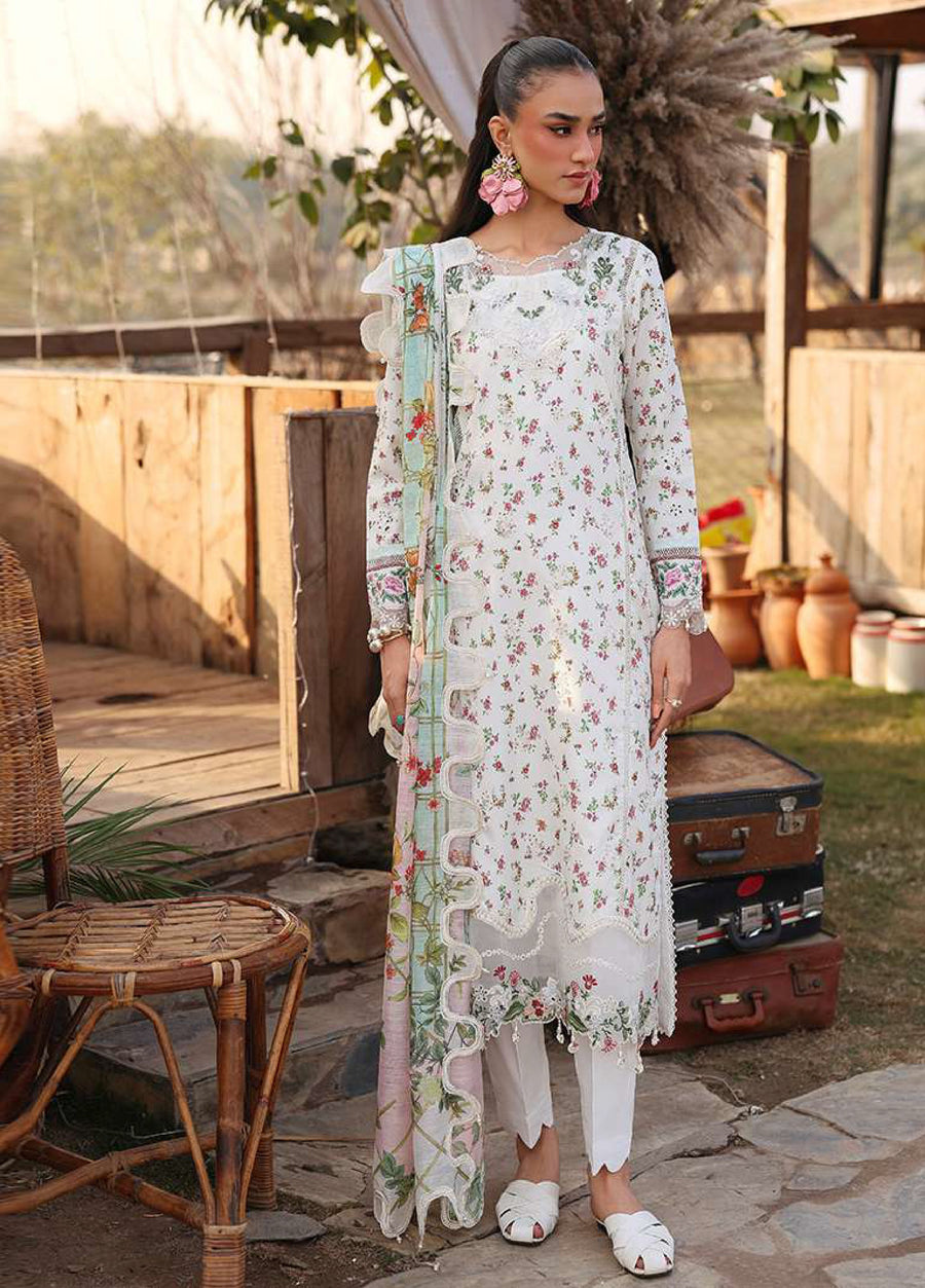 Woman wearing white floral embroidered lawn suit with lace accents and pastel floral dupatta standing outdoors next to wicker chair