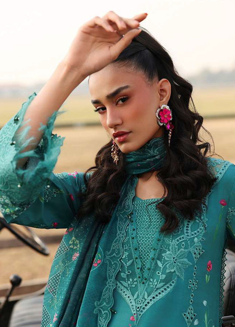 Close-up of woman in teal embroidered suit showing detailed floral embroidery, lace neckline, and statement pink earrings