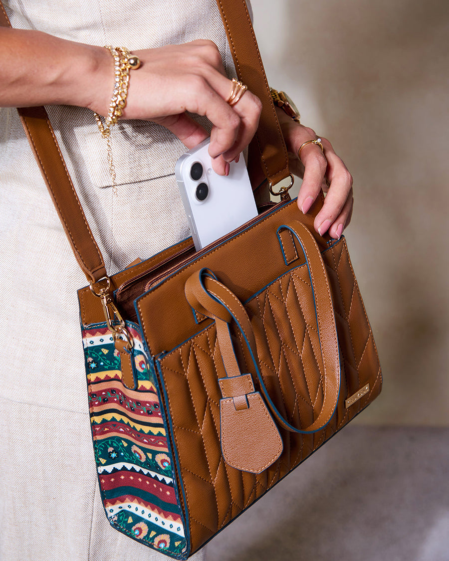 Close-up of woman placing phone into handbag front slip pocket with quilted stitching and patterned sides