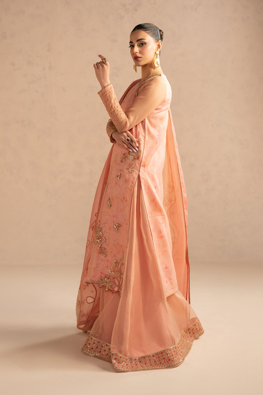 Close-up of model’s embroidered long shirt sleeves with sequin detailing and floral gold embroidery on peach organza fabric