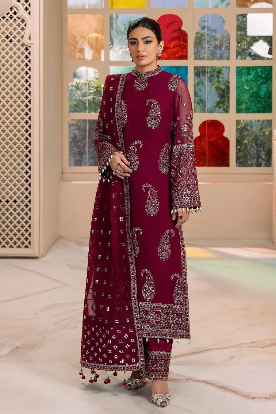 Front view of woman wearing magenta traditional three-piece suit with intricate silver embroidery and patterned dupatta