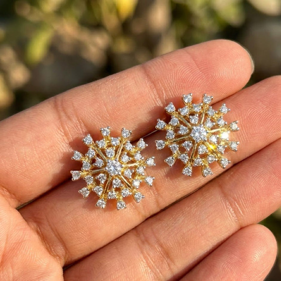 Starburst crystal stud earrings held between fingers under natural outdoor sunlight showing sparkle