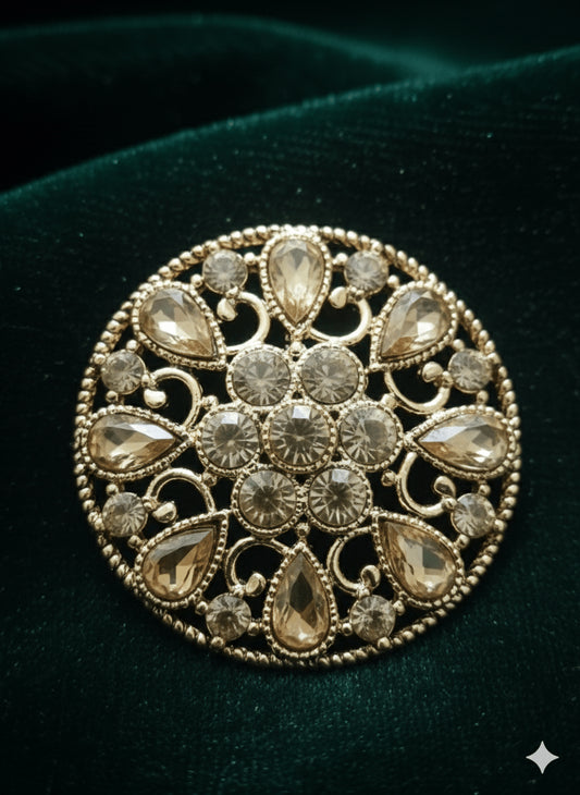 Close-up of a single round gold filigree stud earring featuring detailed floral pattern with teardrop and round crystals