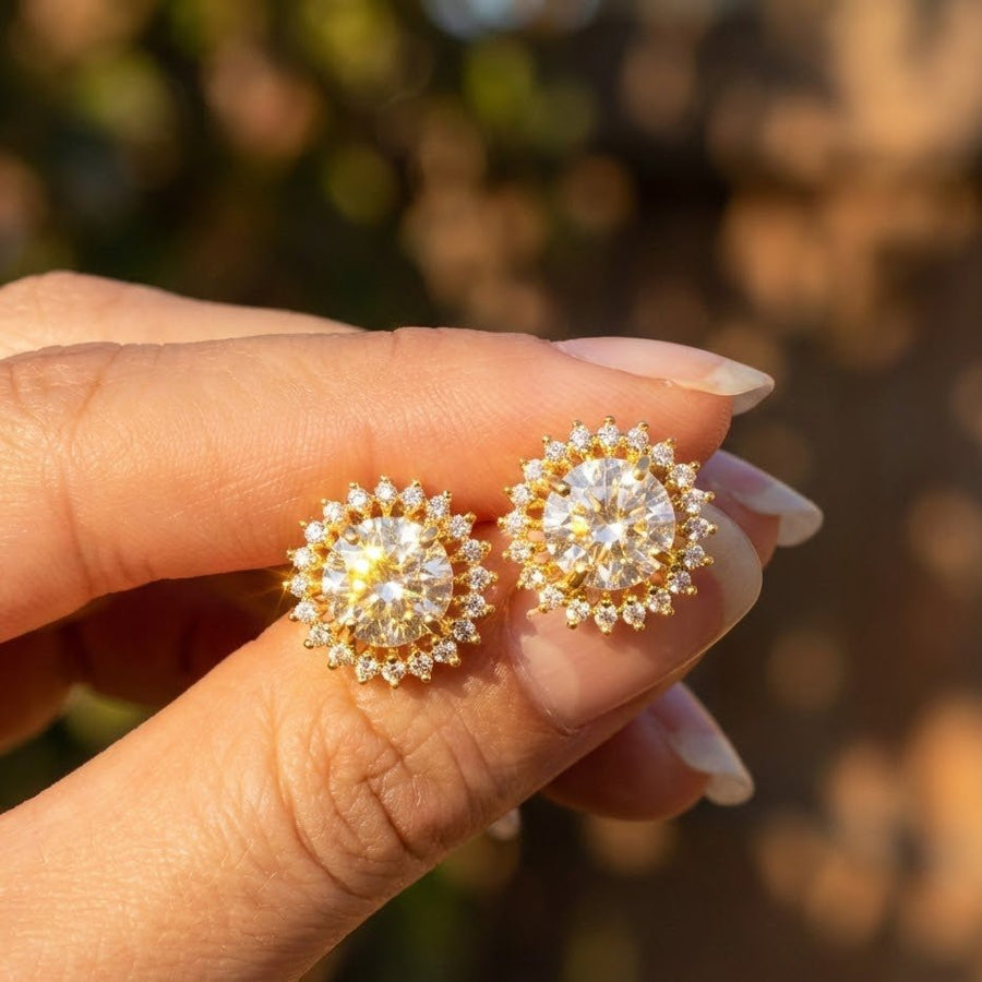 Hand holding clear gemstone halo stud earrings showing sparkle in natural light