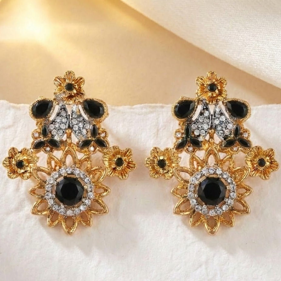 Pink floral gemstone earrings placed artistically on dark textured background with spotlighting