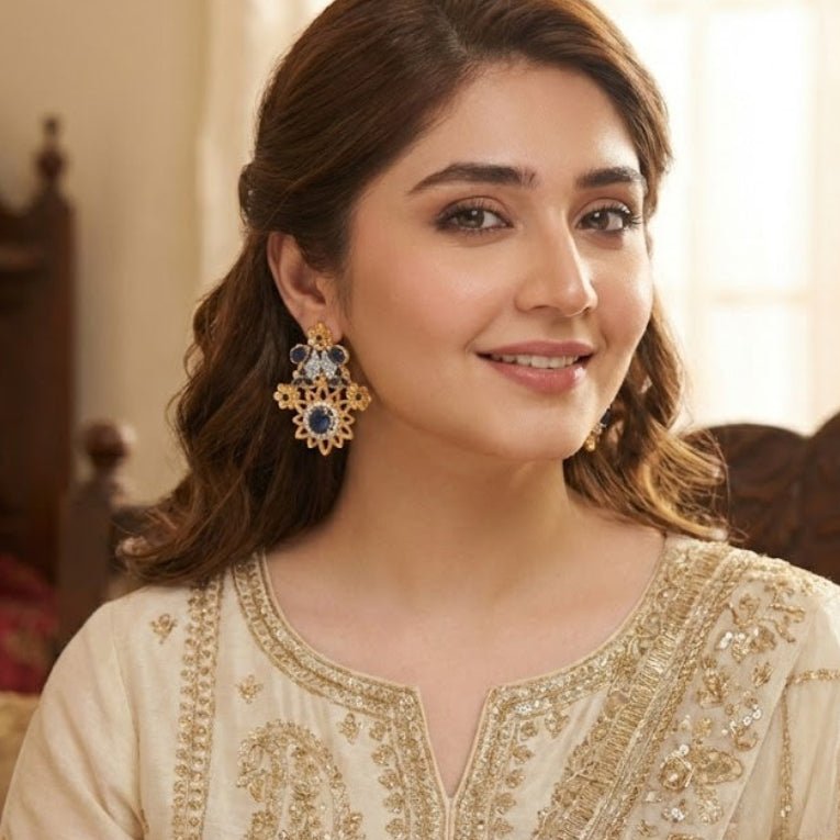 Woman modeling royal blue floral gemstone earrings with ivory embroidered outfit smiling indoors