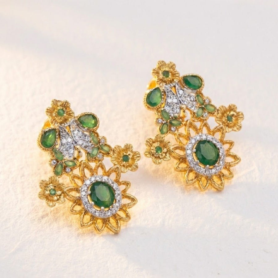 Green floral gemstone earrings with sparkling accents displayed on soft cream fabric in warm light