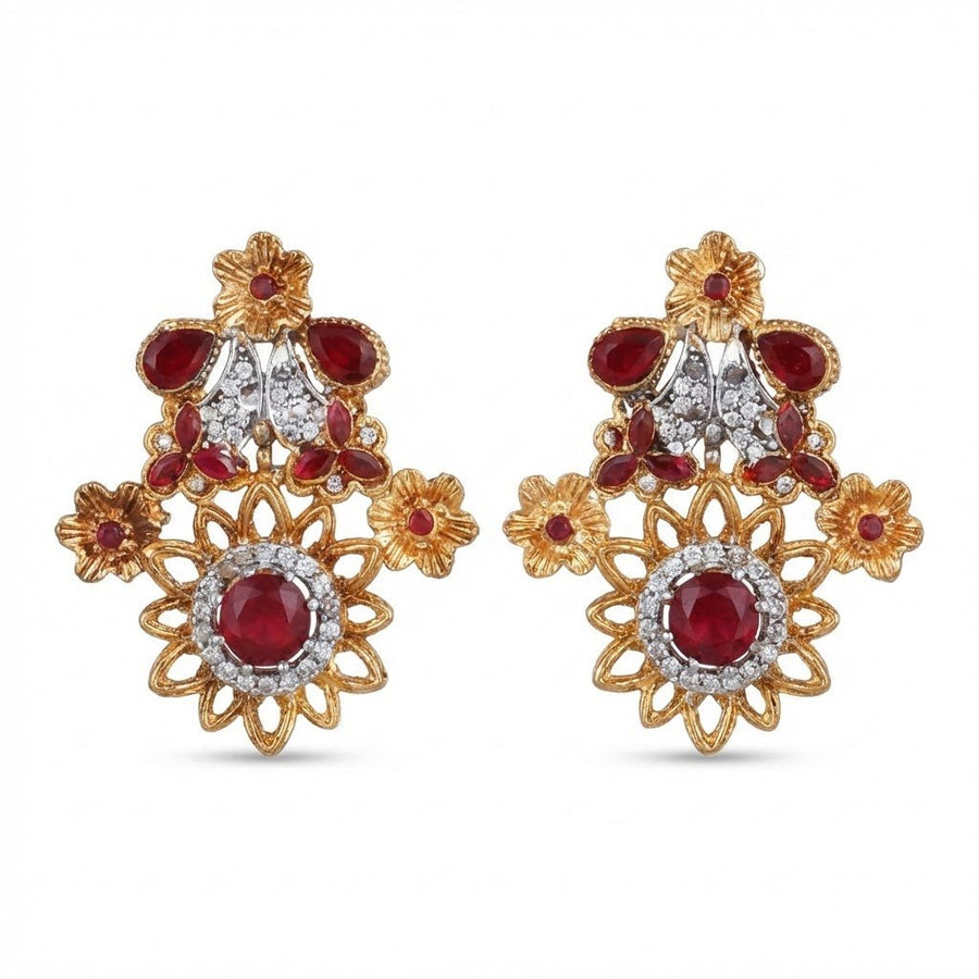 Pair of floral design earrings with deep red gemstones and sparkling white accents set in gold-tone metal on white background