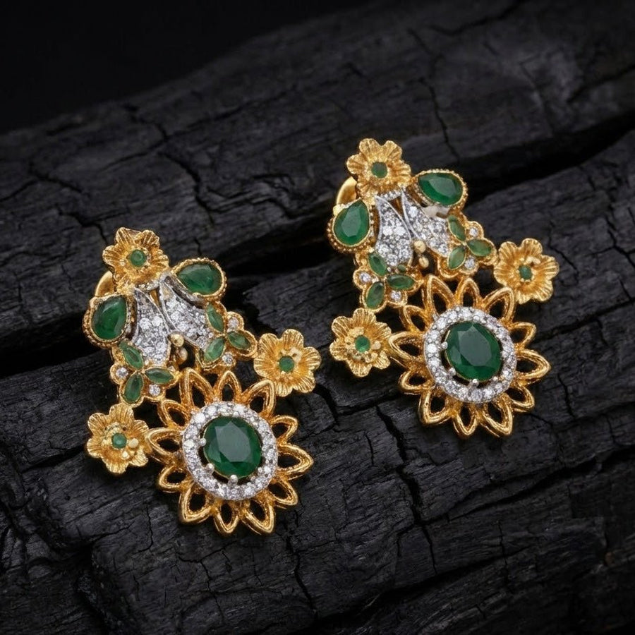 Green gemstone floral earrings arranged on a dark textured surface with soft focused lighting