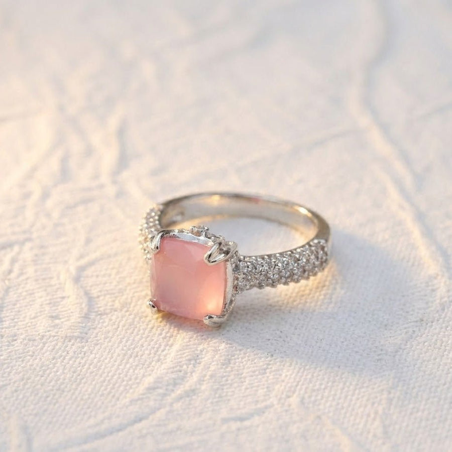 Silver cocktail ring with soft pink cushion-cut gemstone placed on white textured fabric