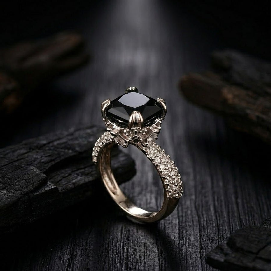 Silver cocktail ring with black cushion-cut gemstone and pave-set accent stones on band