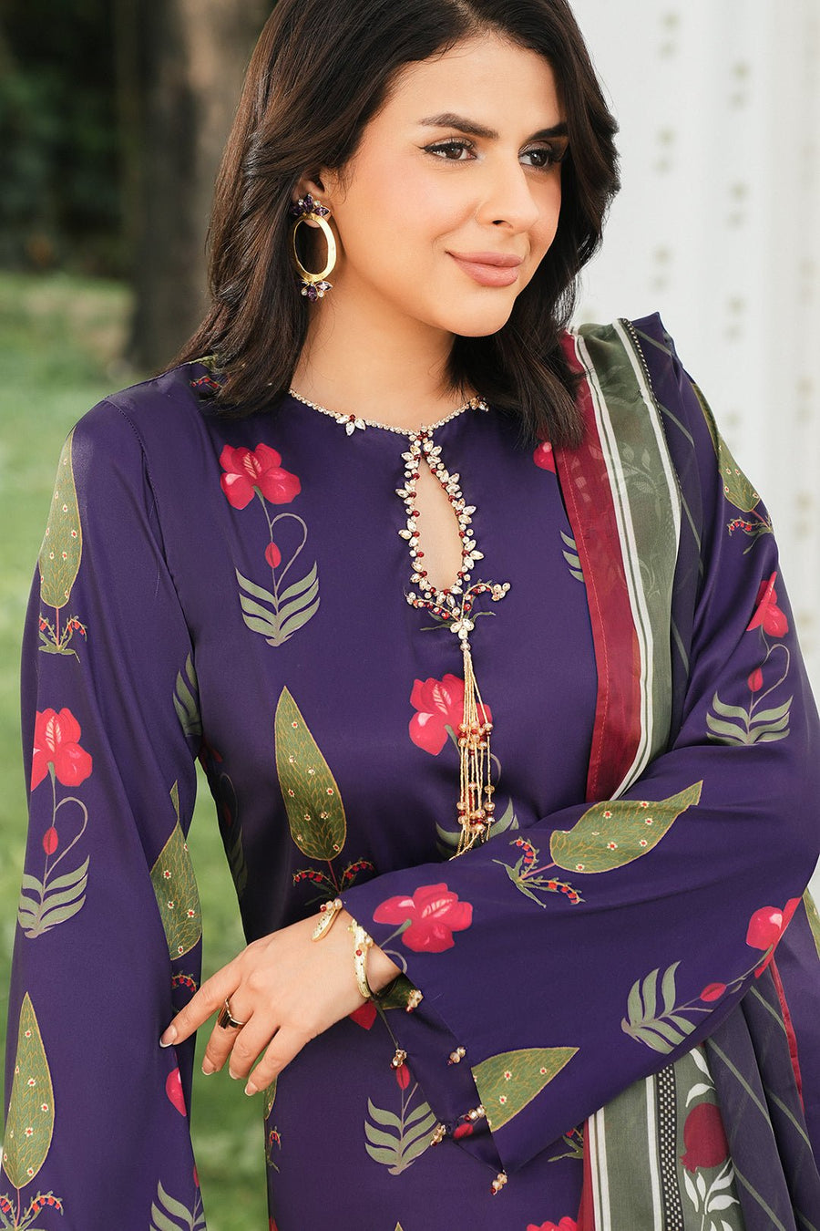 Close-up of woman’s upper body showing detailed bead embellishments on the keyhole neckline and floral print on silk fabric