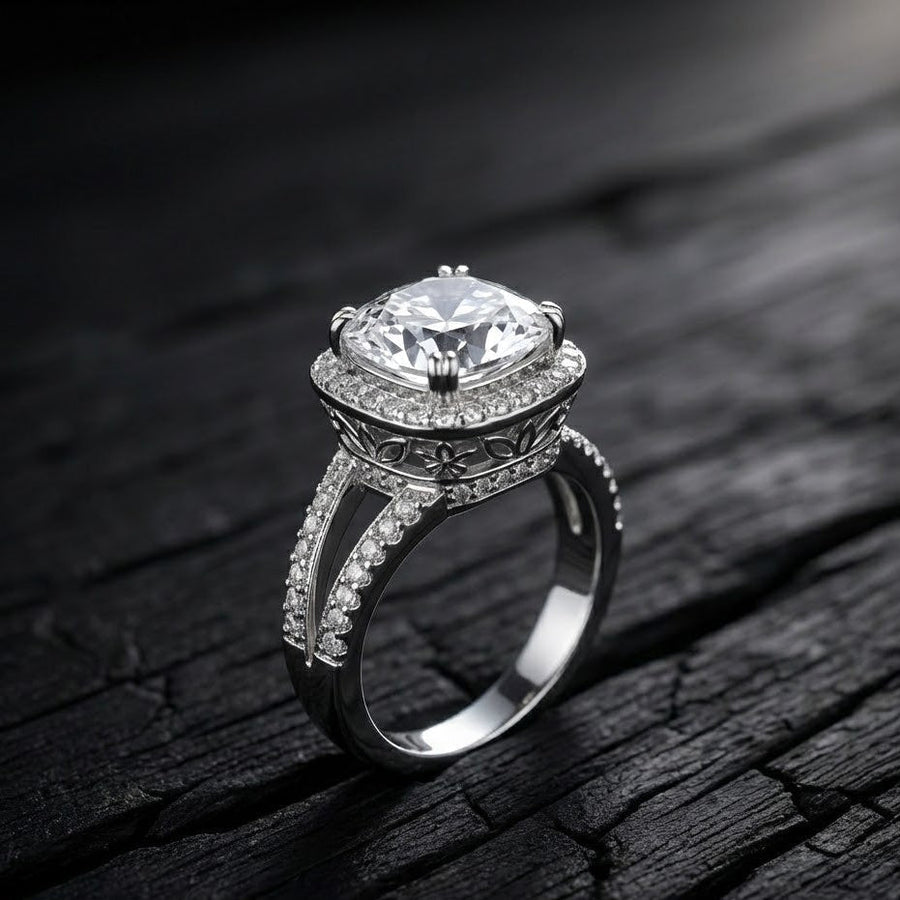 Close-up of cushion-cut clear gemstone ring with double pavé halo and floral engravings on dark textured surface