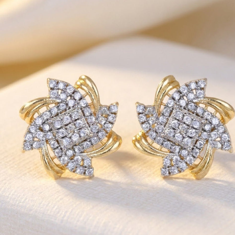 Close-up view of gold-tone floral stud earrings with clear crystals on a light surface