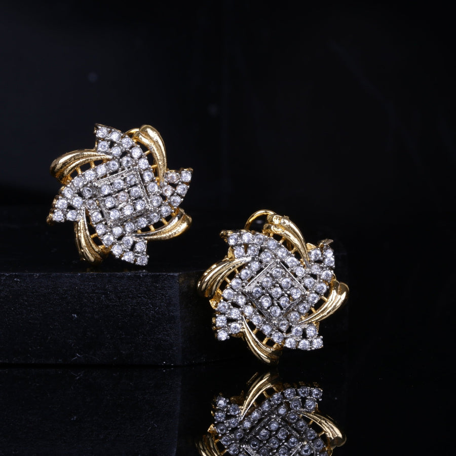 Gold and crystal floral stud earrings reflecting on a black surface with dark background