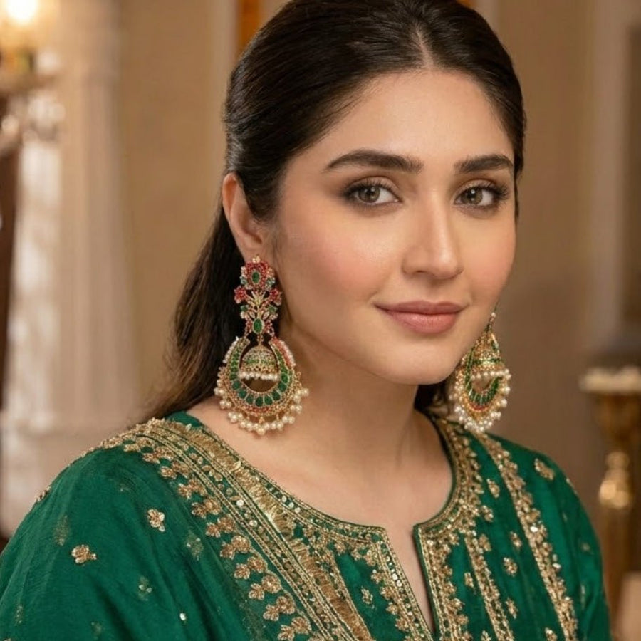 Model showcasing green-and-gold-tone jhumka earrings perfectly coordinated with green embellished ethnic wear