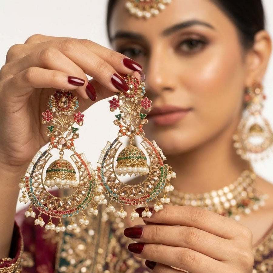 Woman wearing gold-toned jhumka earrings with clear and pink stones styled with beige embroidered traditional outfit