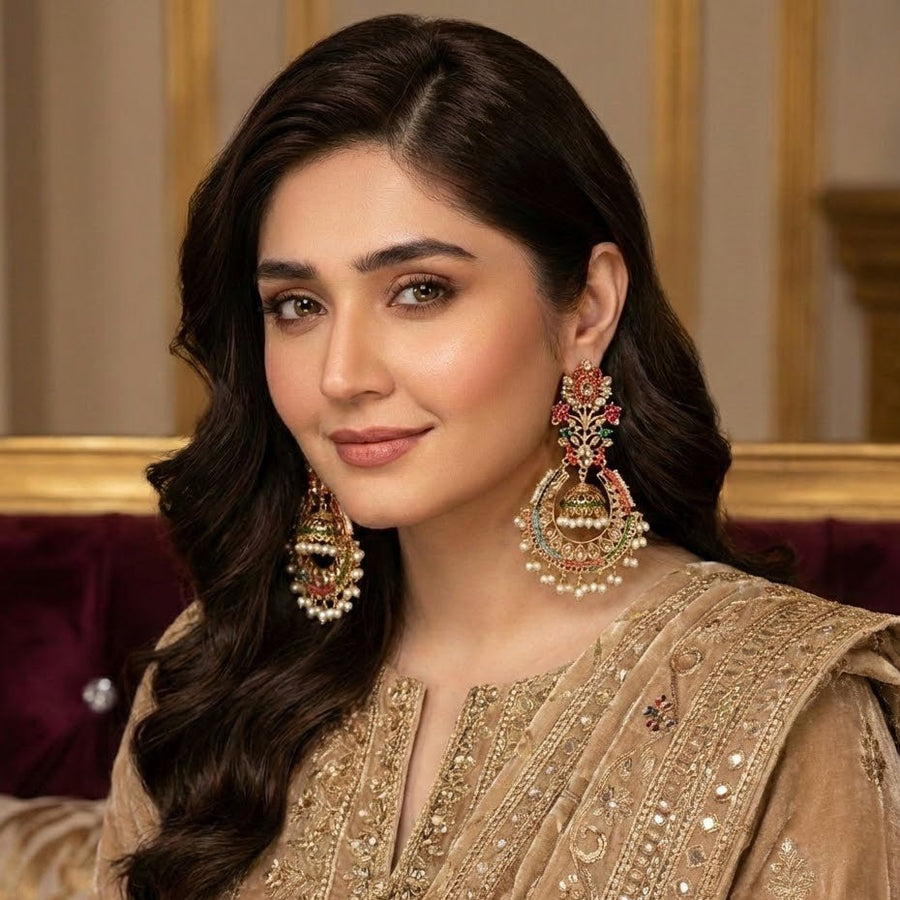 Model elegantly styled in traditional attire wearing statement jhumka earrings with intricate stone and pearl detailing