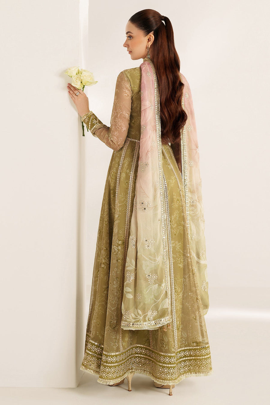 Close-up side portrait of woman admiring embroidered floral sleeve details with sequined borders on formal Anarkali dress
