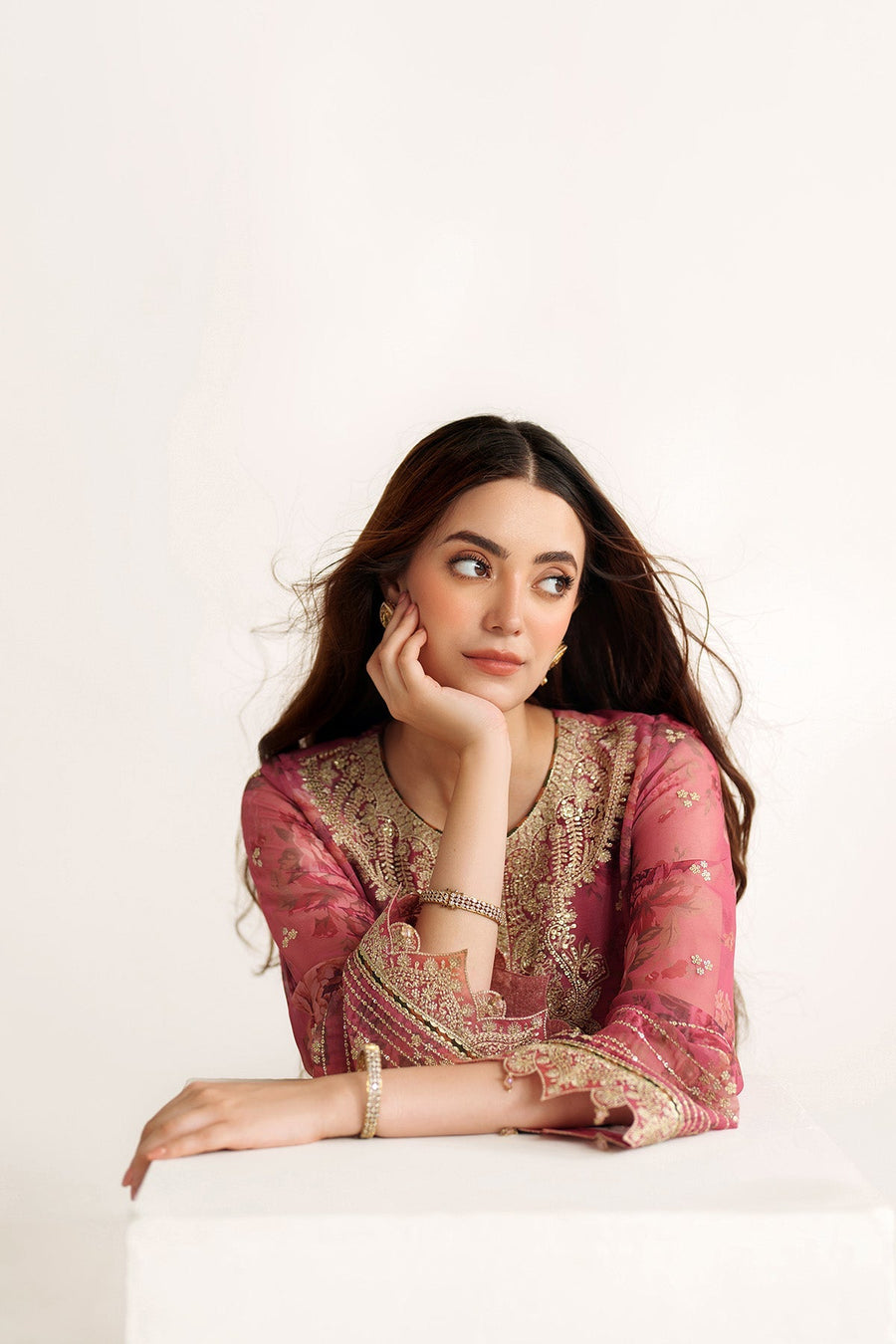 Close-up portrait of woman wearing mauve-pink embroidered suit with delicate gold detailing