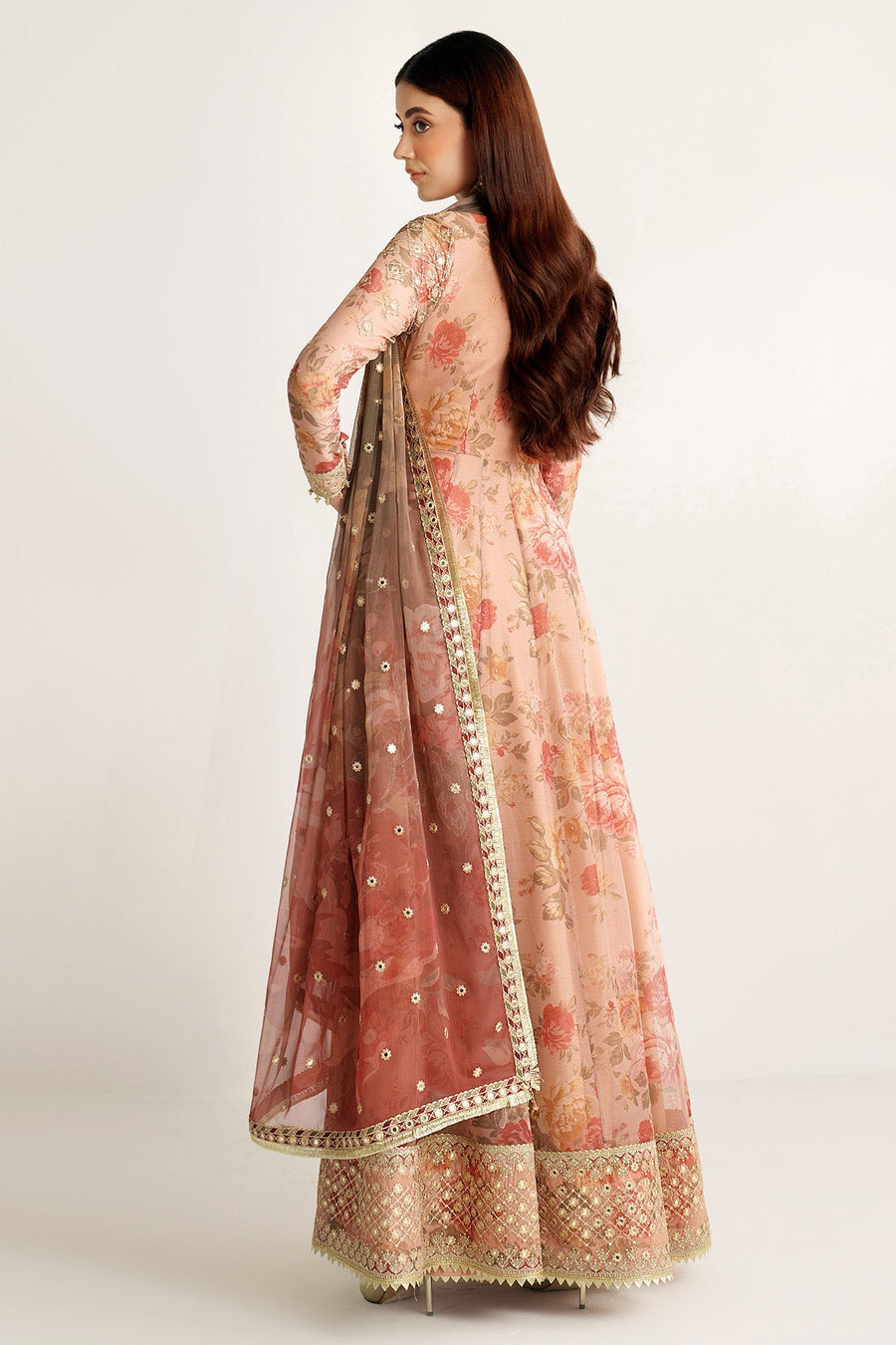 Full length view of woman standing in floral chiffon Anarkali suit with gold embellishments and embroidered hem