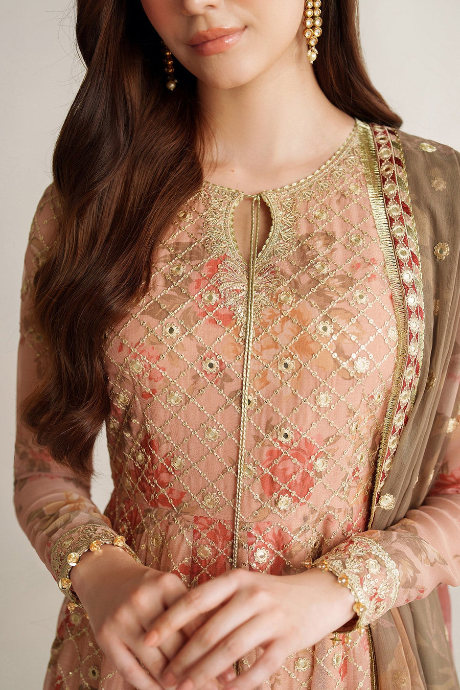 Side view of woman wearing peach Anarkali suit with long embroidered dupatta draped over shoulder