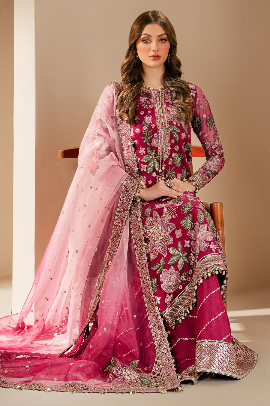 Model seated showcasing detailed floral embroidery on magenta suit paired with sheer pink embroidered dupatta