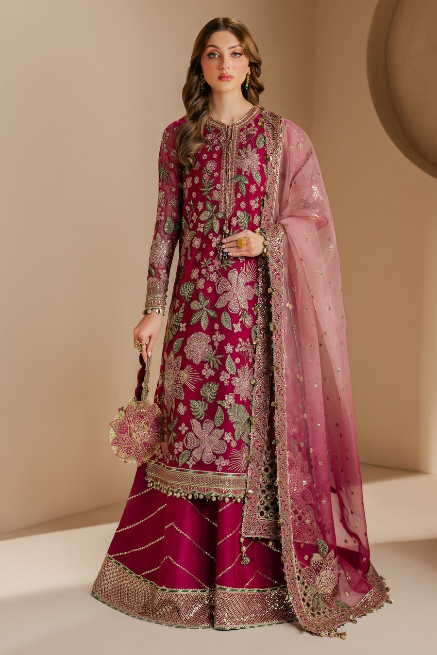 Closeup of model featuring detailed floral embroidery and tassels on magenta fabric with sheer pink dupatta