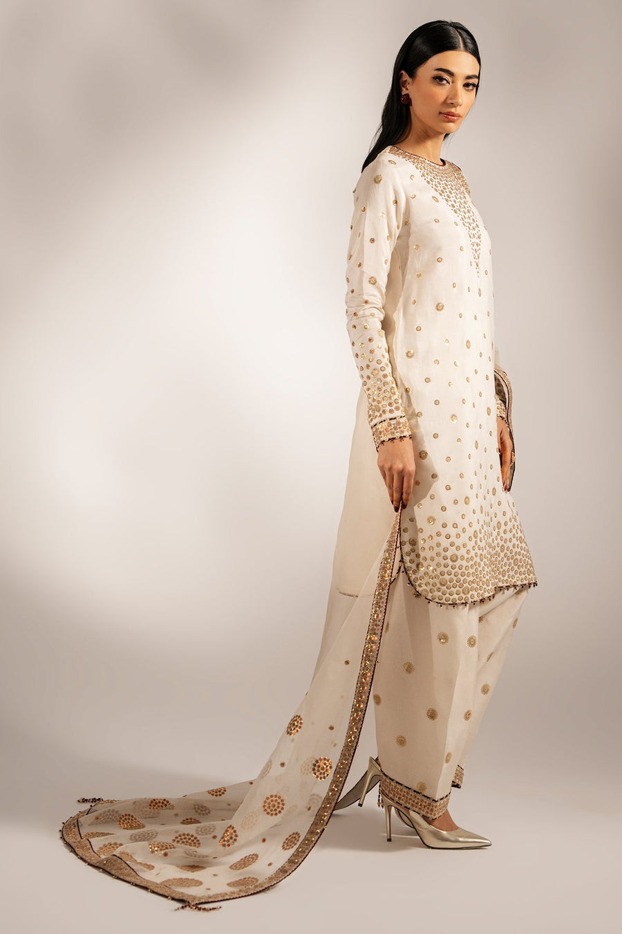 Side view of model showing detailed embroidery on sleeve cuff and pants of the formal suit.