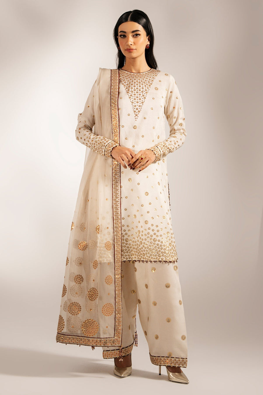 Front view of model wearing cream raw silk embroidered Pakistani formal suit with matching dupatta and trousers.