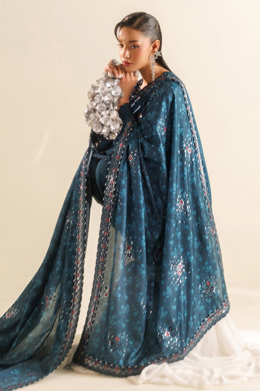 Detailed view of embroidery and embellishments along trouser hem and shawl border.