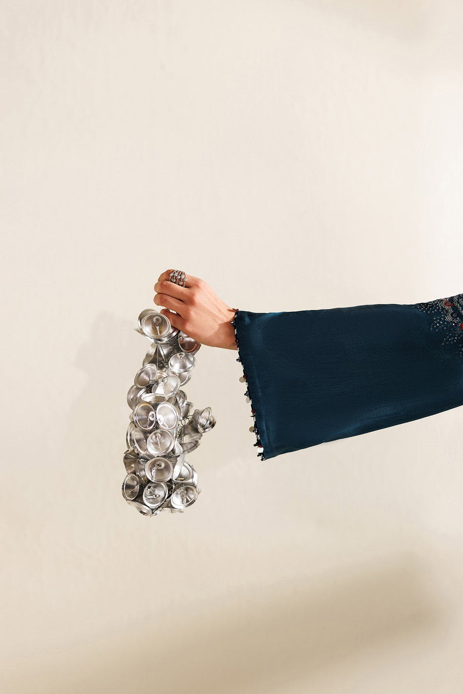 Model standing in full ensemble with dupatta spread showcasing embroidery, print, and accessory details in deep teal.