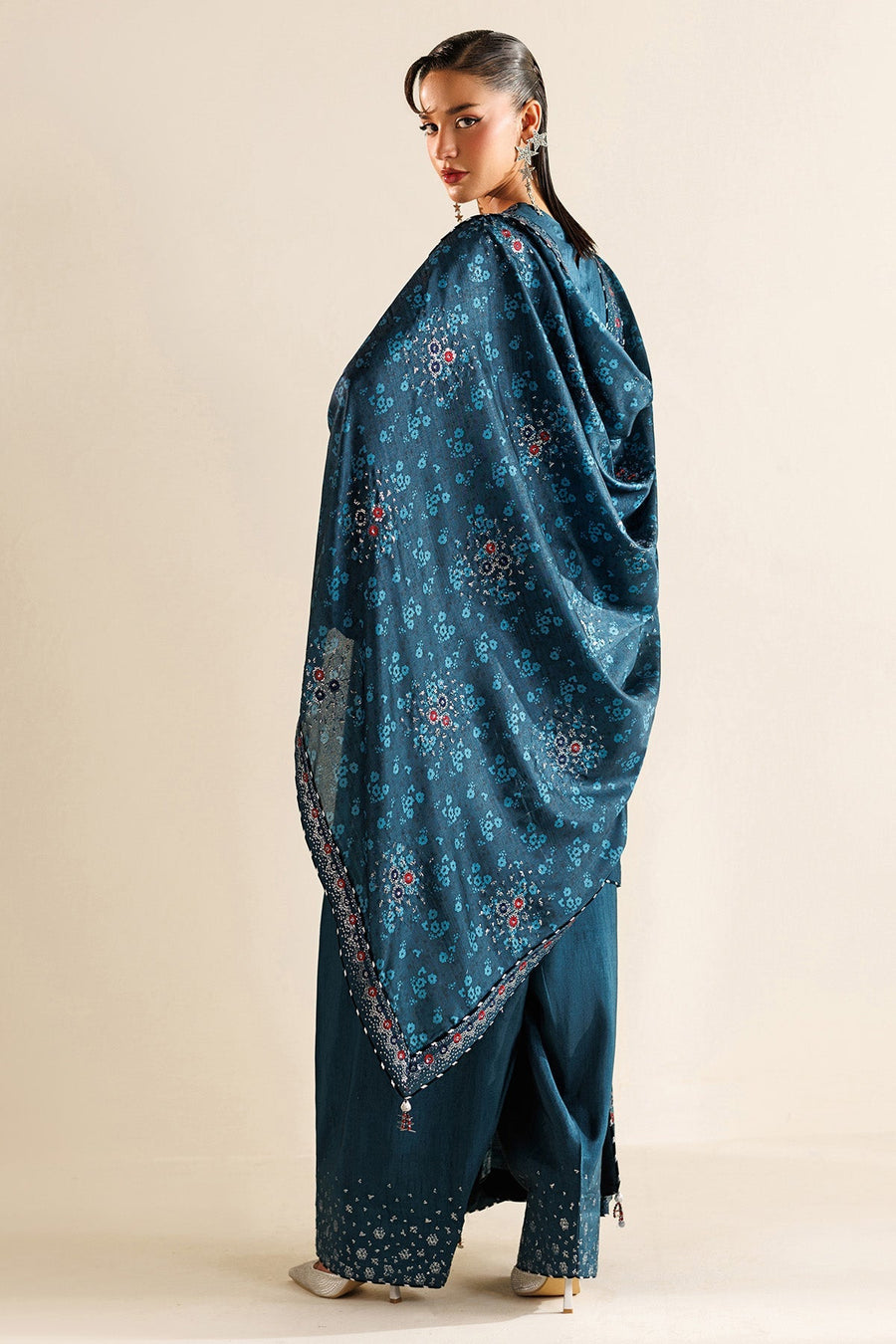 Full front view of woman in elegant teal winter suit with wide-leg trousers and floral embroidery details.