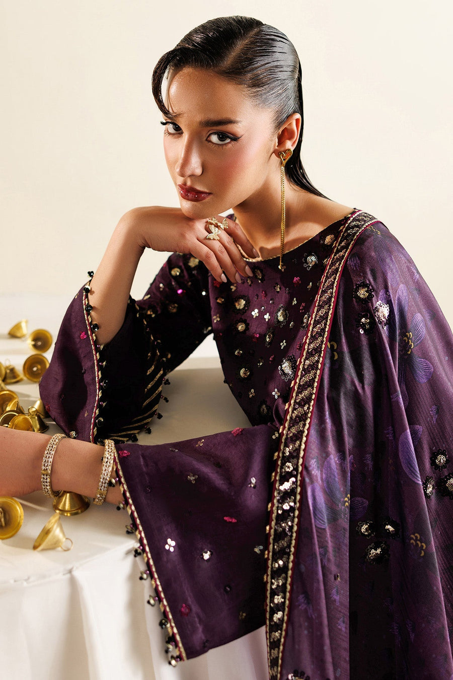 Close-up of embroidered sleeve and detailed sequin work on deep plum raw silk fabric