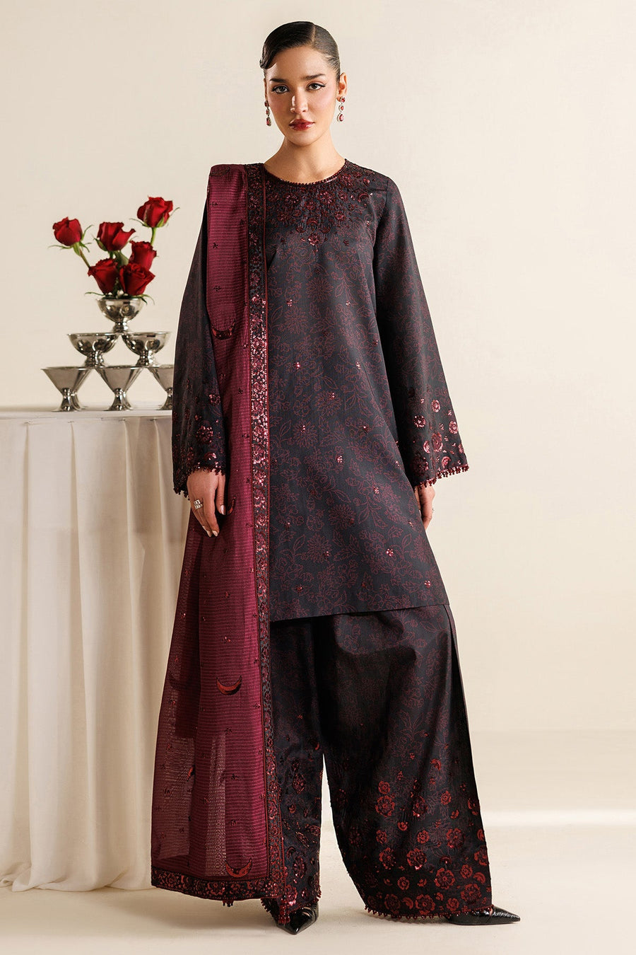 Close-up of the neckline featuring deep maroon sequin embroidery on black fabric, showing intricate floral patterns and bead detailing around collar and sleeves.