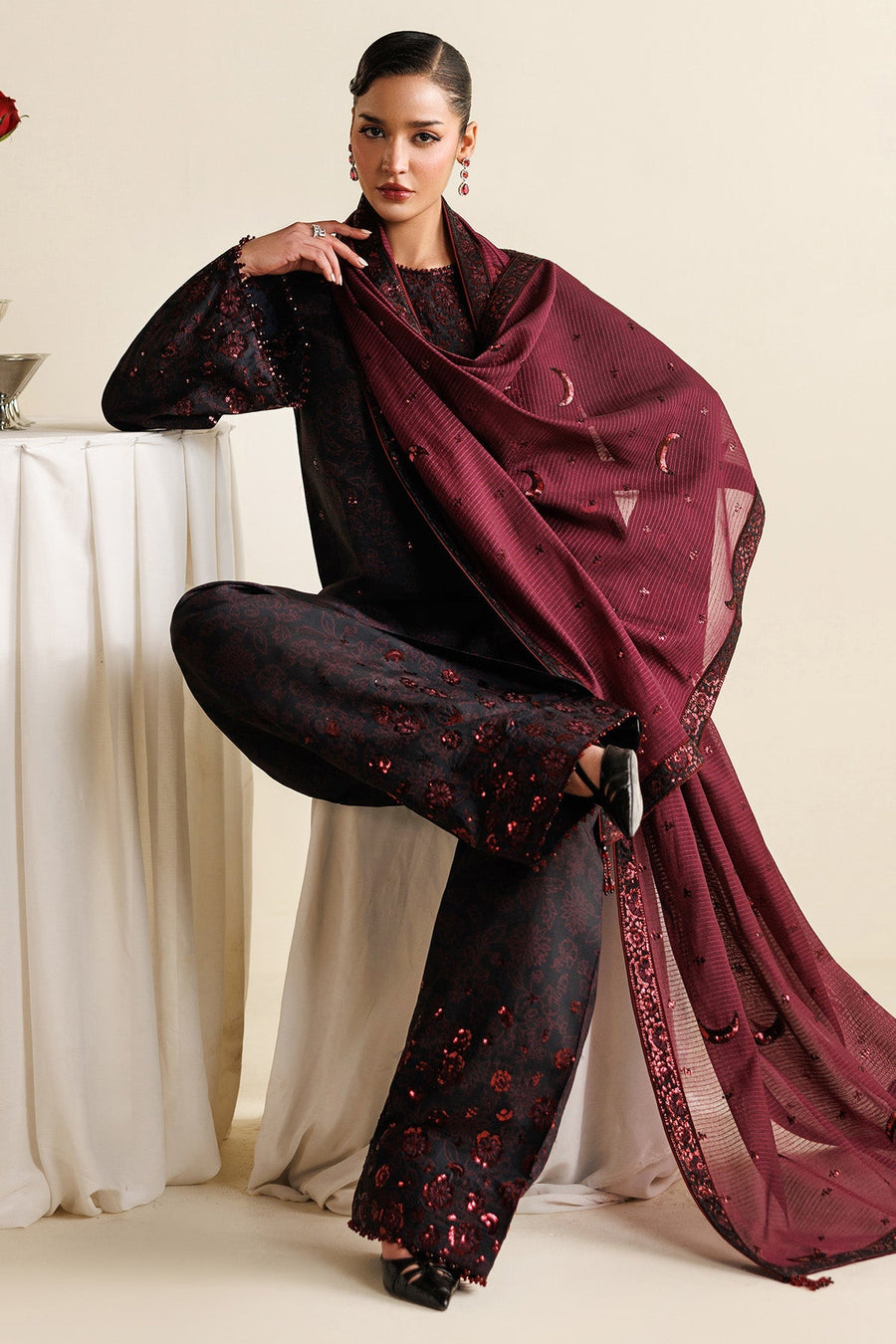 Full view of model posing with maroon dupatta flowing, showing the three-piece unstitched suit with rich floral embroidery and crescent sequin accents.
