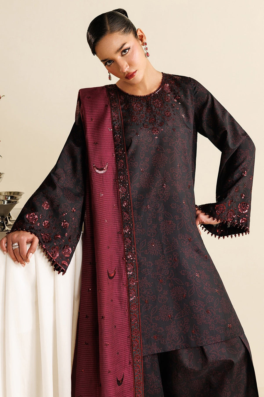 Model draped in sheer maroon dupatta embroidered with sequined crescent and floral patterns, complementing the black embroidered suit.