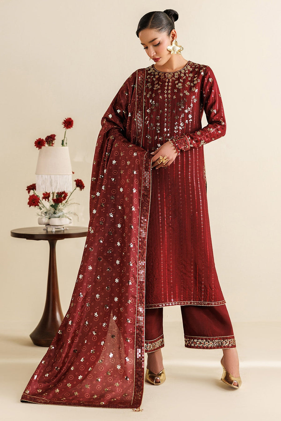 Front view of woman wearing embroidered maroon festive suit holding matching dupatta