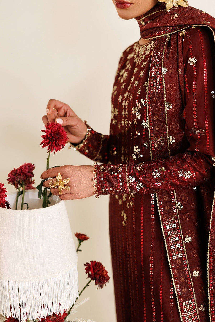 Close-up of woman’s face showing gold floral earrings and embroidered maroon dupatta