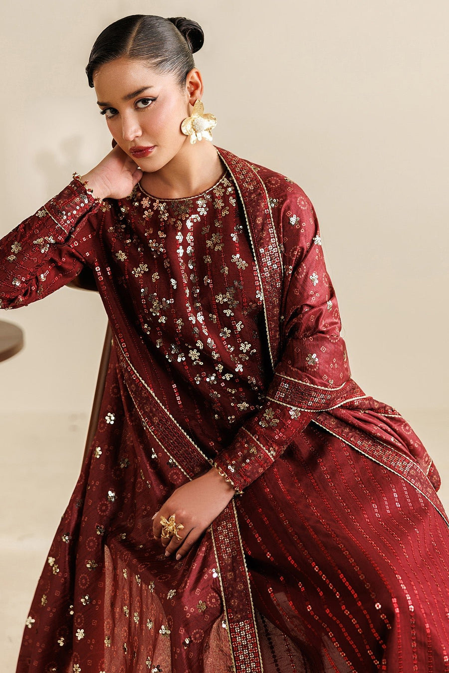Low angle of maroon embroidered suit pants showing embellished borders near ankles